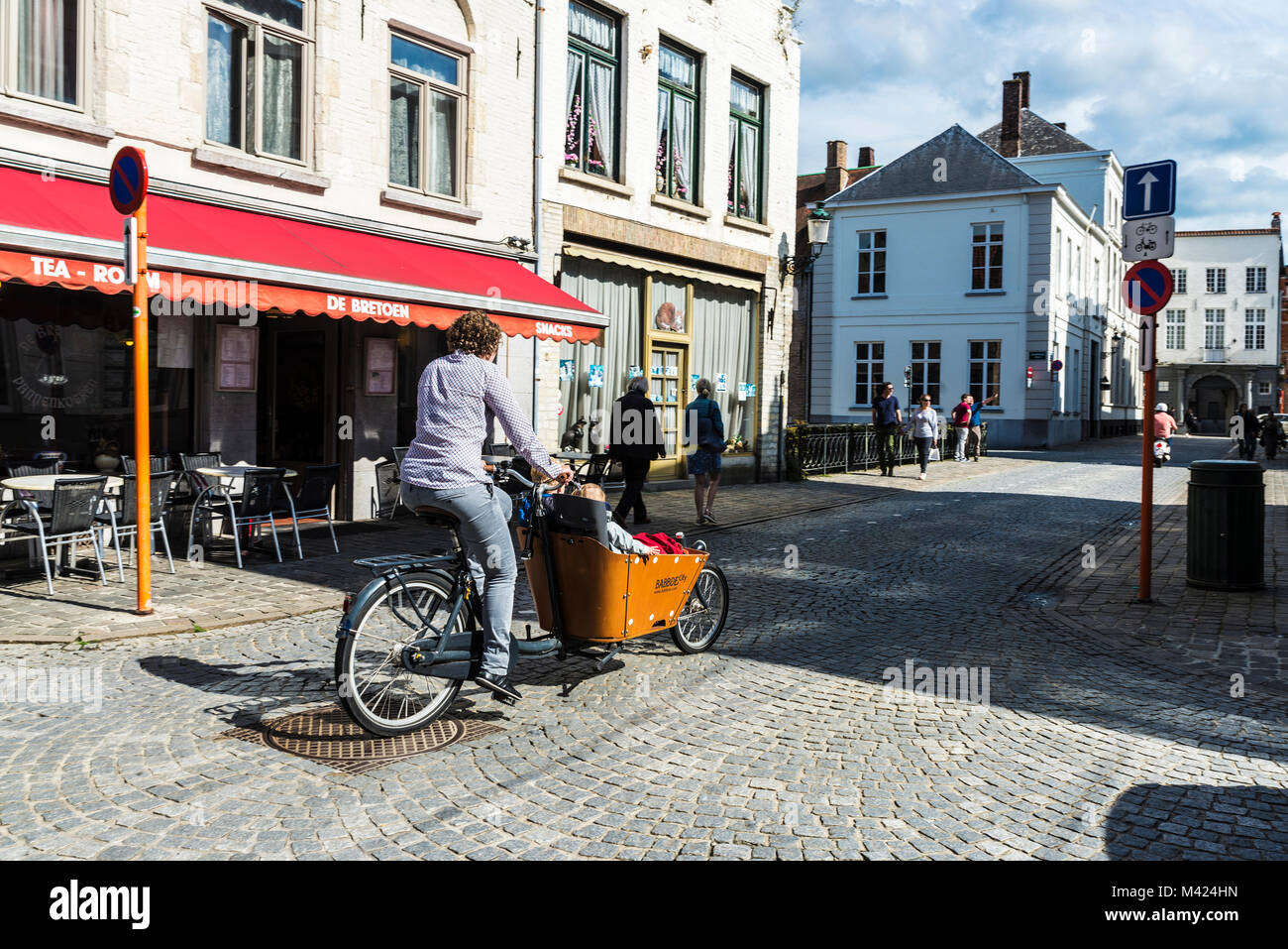 Bruges, Belgio - 1 Settembre 2017: Street con le persone camminare e una donna in bicicletta con un Babboe bicicletta con i bambini nella città medievale di Bruges Foto Stock