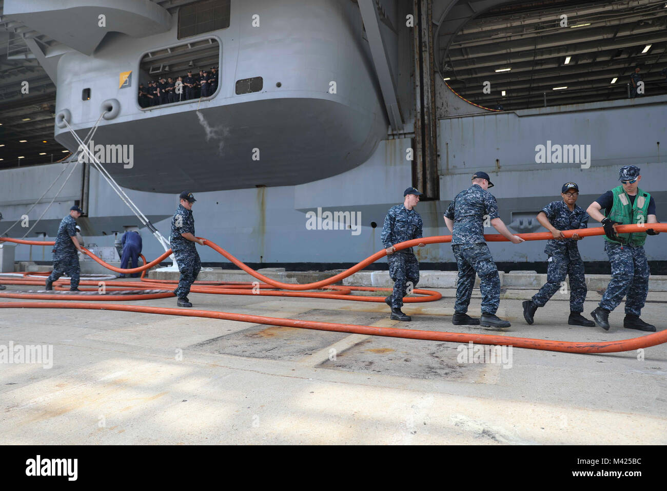 170725-N-NN369-151 NORFOLK (25 luglio 2017) velisti assegnati alla Nimitz-class portaerei USS Abraham Lincoln (CVN 72), gestire i cavi di alimentazione per la Nimitz-class portaerei USS Harry Truman (CVN 75), come Harry Truman tira in Naval Station Norfolk dopo aver completato le prove in mare. Abraham Lincoln è ormeggiata in Norfolk per un vettore disponibilità incrementale in preparazione per workups. (U.S. Foto di Marina di Massa lo specialista di comunicazione di terza classe Jessica Paulauskas/rilasciato) Foto Stock