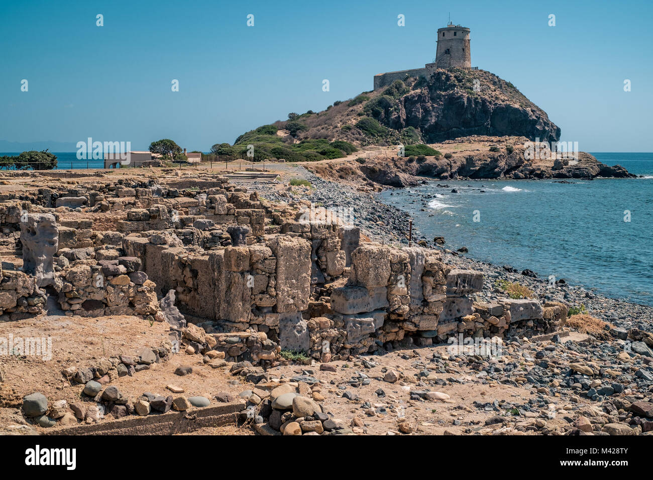 La torre di guardia e le antiche rovine romane e pre-romane della penisola di Nora. Famoso sito archeologico nei pressi di Cagliari, Sardegna, Italia. Foto Stock