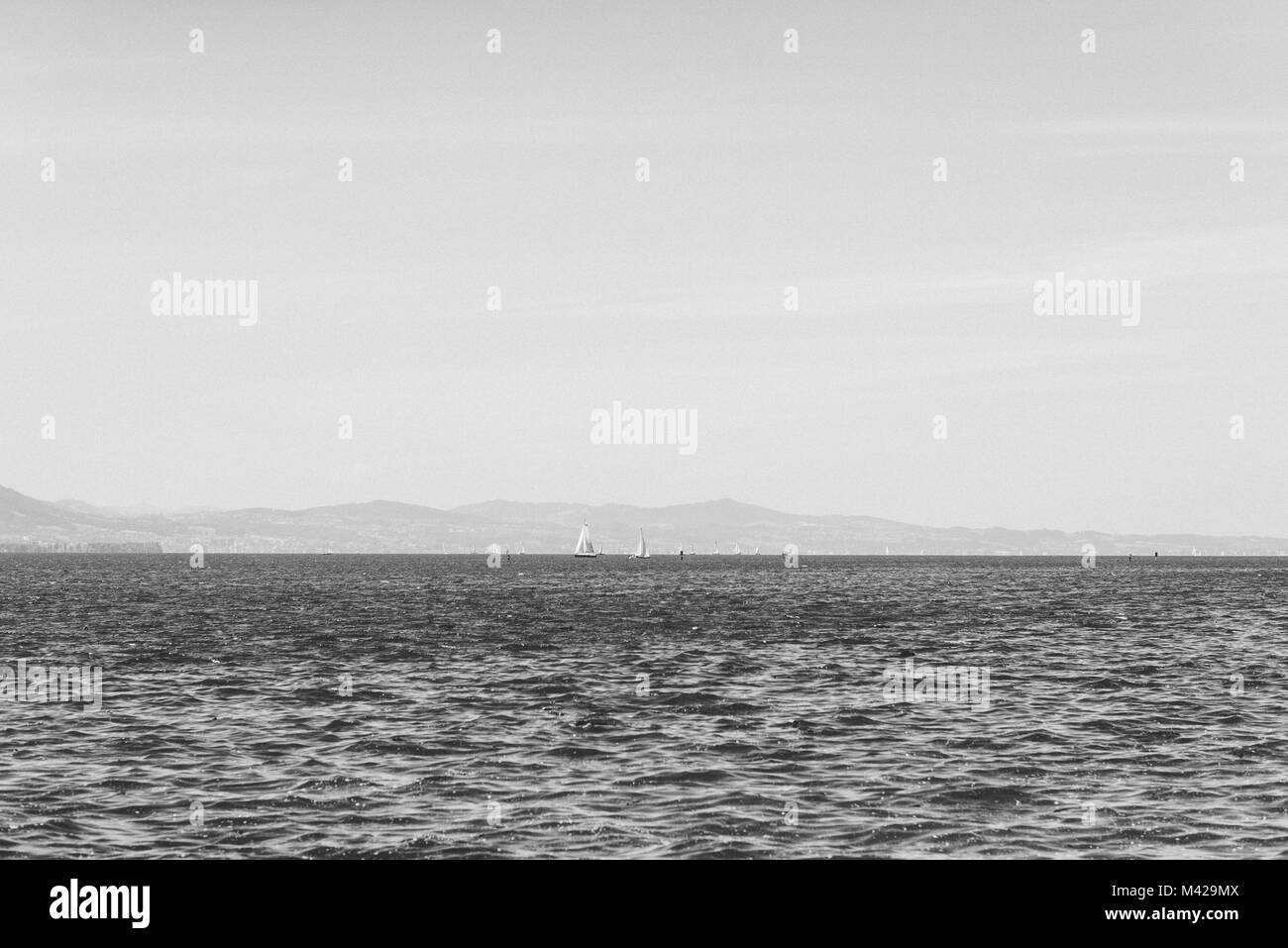 Immagine in bianco e nero presi in Lindau in Germania. Una bella immagine orizzontale del Bodensee con alcune barche a vela all'orizzonte. Foto Stock