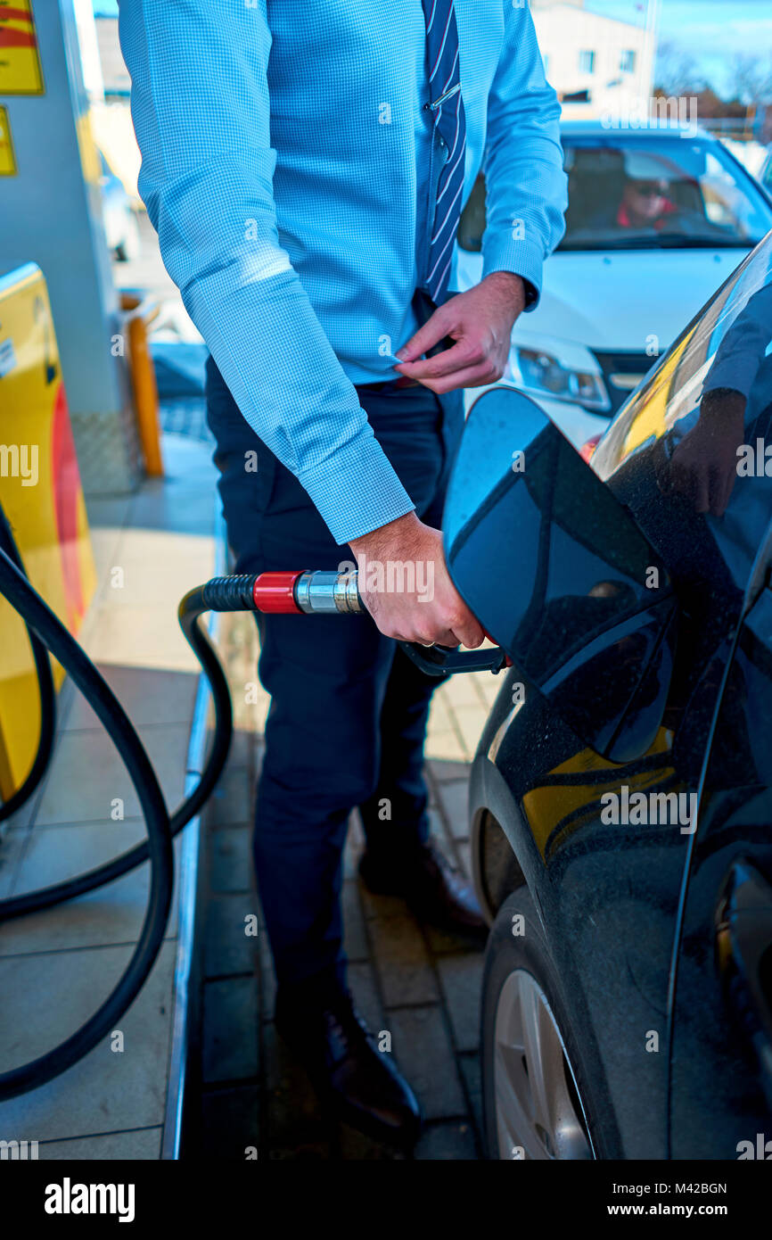 L'uomo riempie la macchina in corrispondenza di una stazione di gas Foto Stock