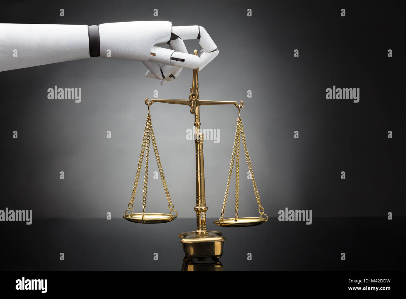 Close-up di un robot la mano che tiene la giustizia scala su sfondo grigio Foto Stock