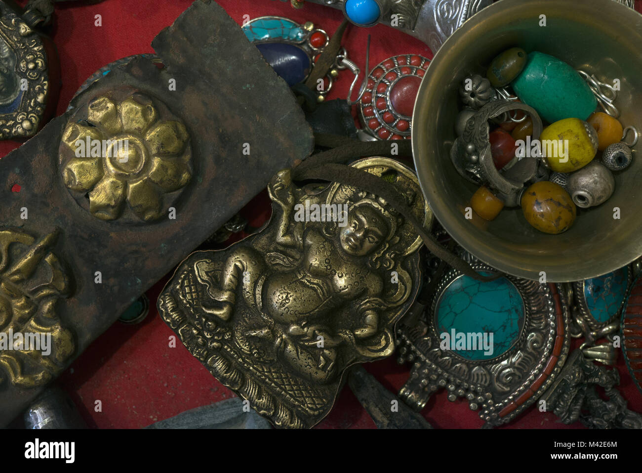 Antichi oggetti religiosi cultura tibetana: rame statuetta di Buddha, una ciotola con il vecchio perline di turchese e ambra in una ciotola di pietra, una cintura di cuoio Foto Stock