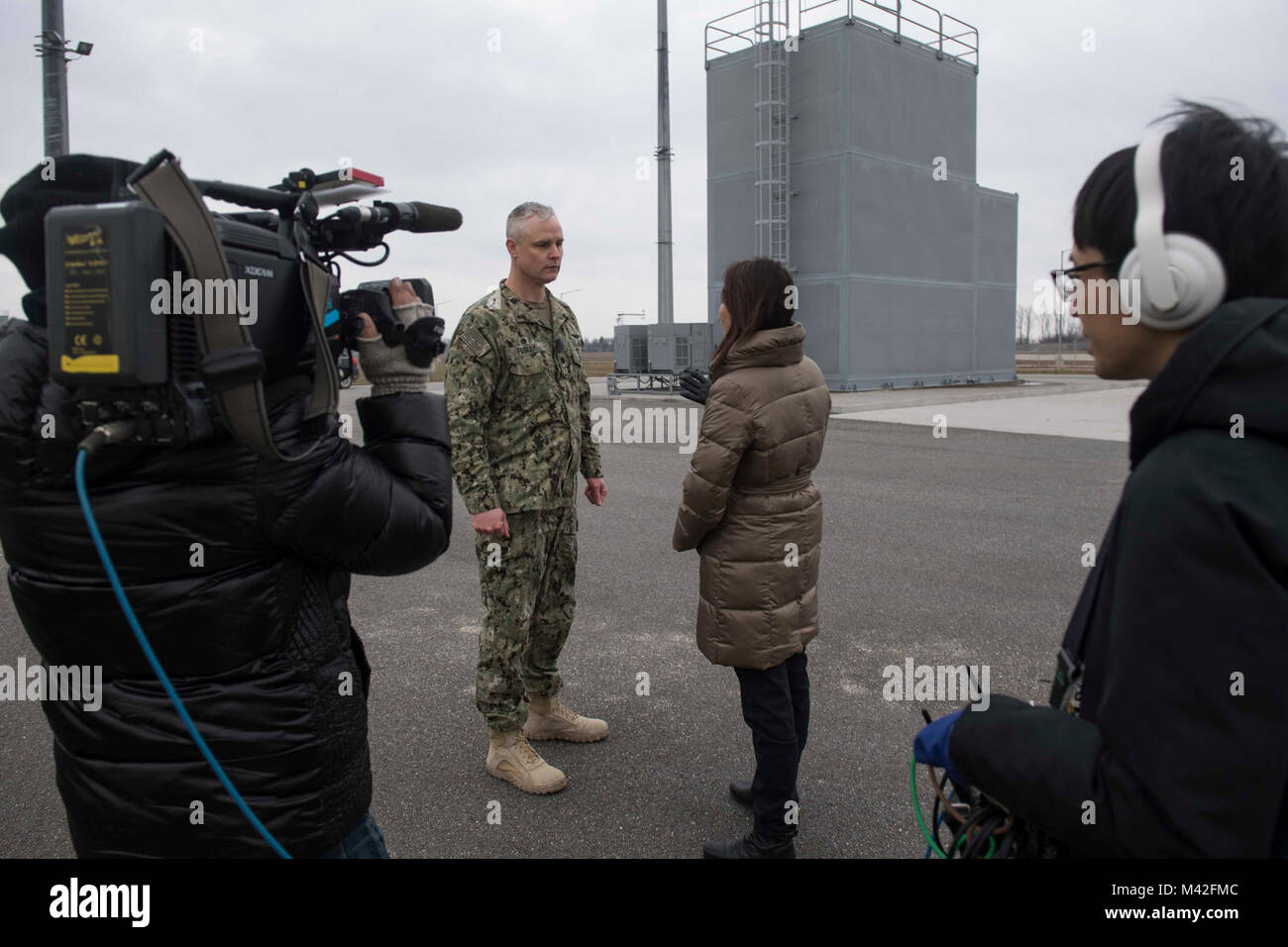 A terra il sistema di difesa missilistica, Romania (feb. 7, 2018) della Cmdr. Contrassegnare Fegley, centro sinistra, comandante della egida a terra il sistema di difesa missilistica (AAMDS) Romania, è intervistato da supporti in giapponese uscita TV Asahi anchor Tomoko Nagano, centro a destra durante una prevista media imbarcarsi. Supporto navale Facility Deveselu AAMDS e Romania sono co-localizzato con il rumeno 99th Base Militare e gioca un ruolo chiave nel missile balistico di difesa in Europa orientale. (U.S. Navy Foto Stock