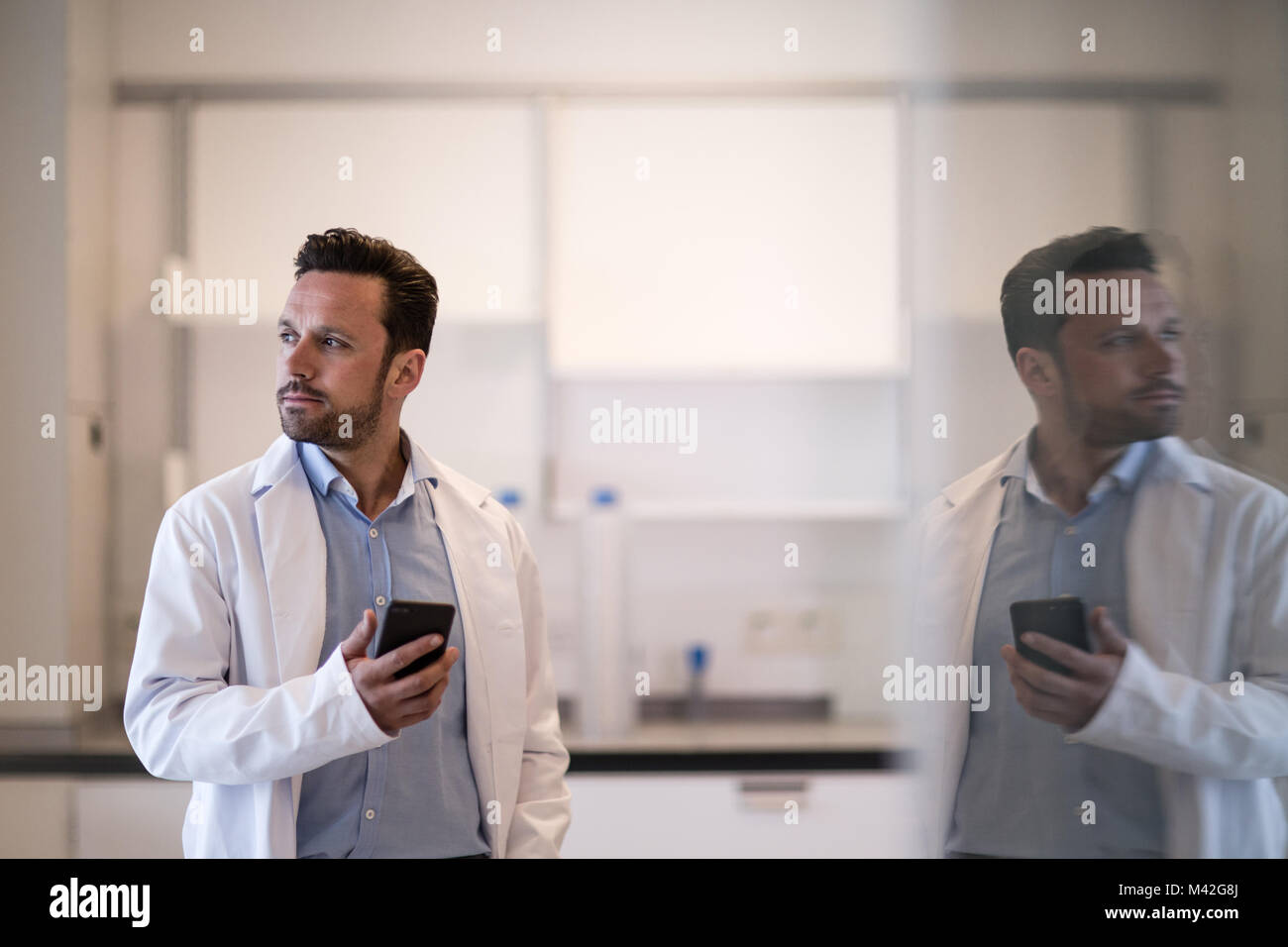 Scienziato maschio utilizza lo smartphone in laboratorio Foto Stock