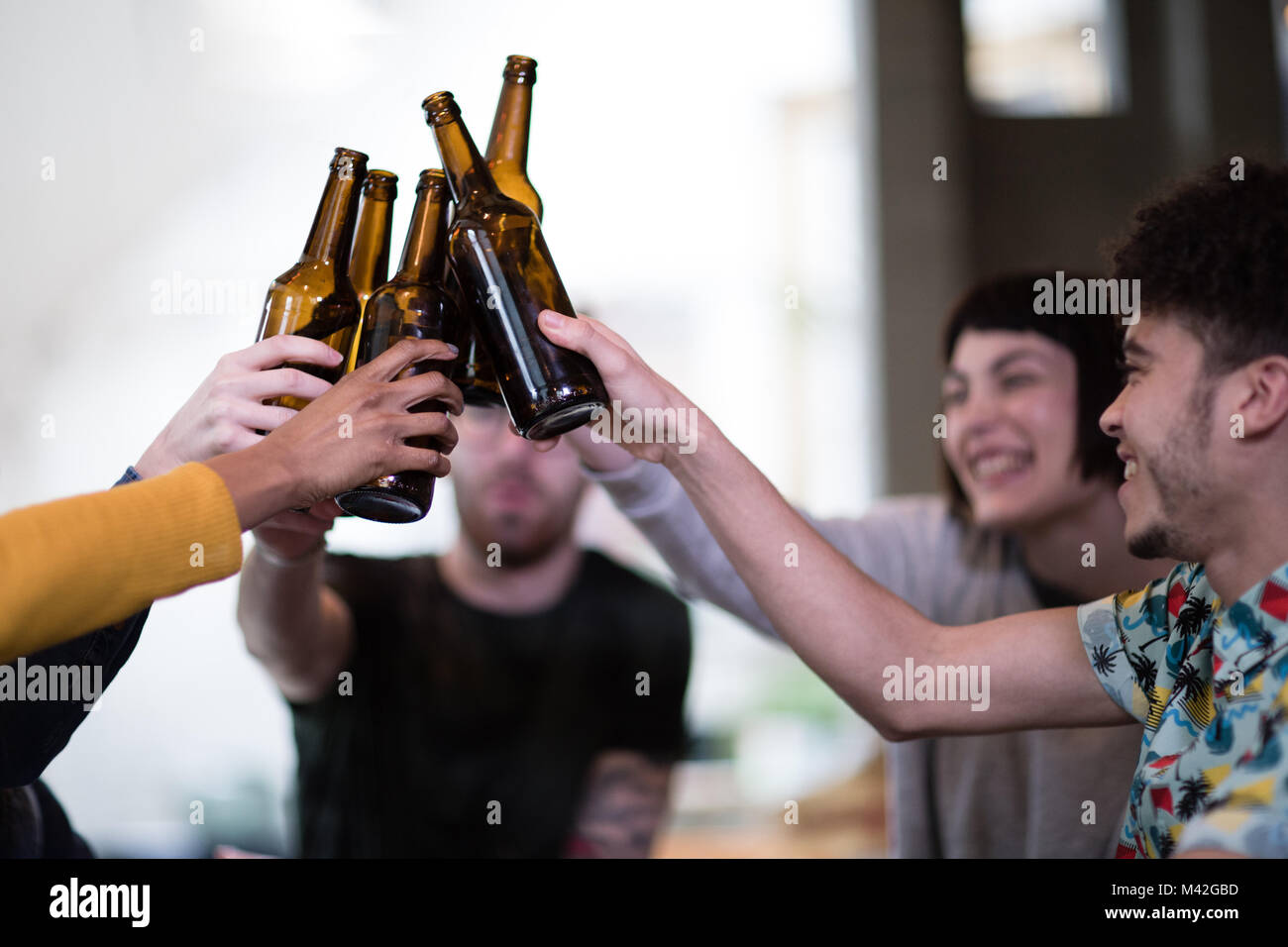 Gruppo di amici tintinnio di bottiglie di birra ad un house party Foto Stock