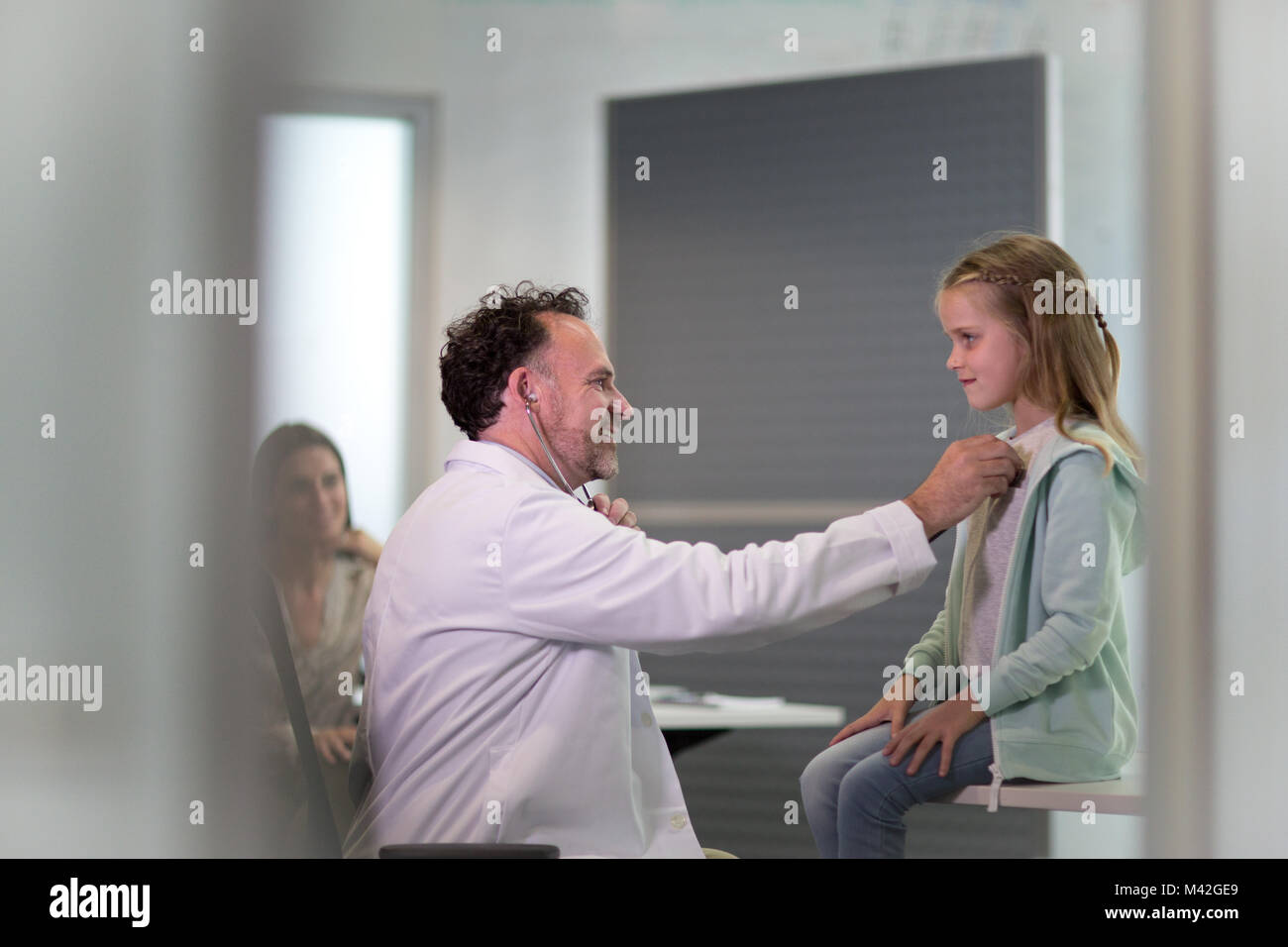 Voce maschile Medico ascoltando childs heartbeat Foto Stock