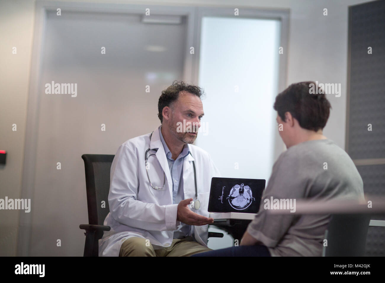 Voce maschile Medico per spiegare i risultati di scansione per il paziente Foto Stock