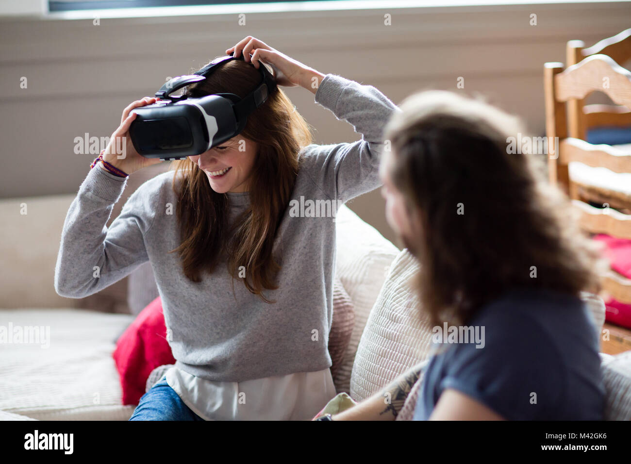 Giovane femmina adulta mettendo su auricolare VR Foto Stock