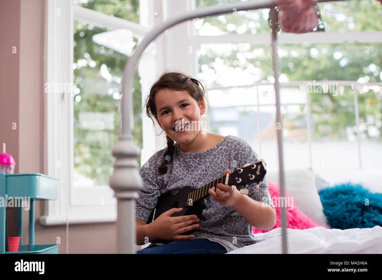 Ragazza che gioca un ukulele guardando la fotocamera Foto Stock