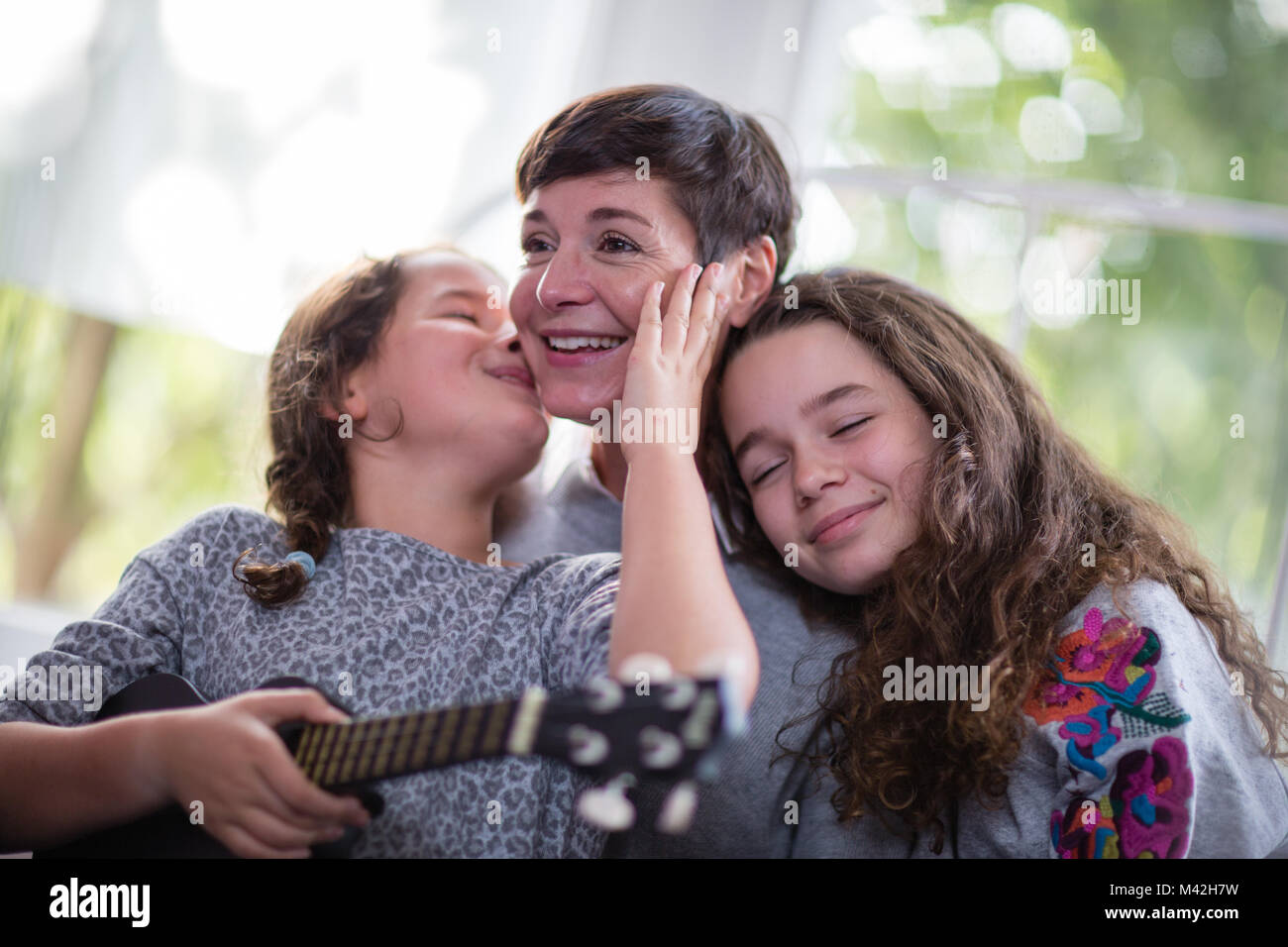 Le figlie baciando e abbracciando la mamma Foto Stock