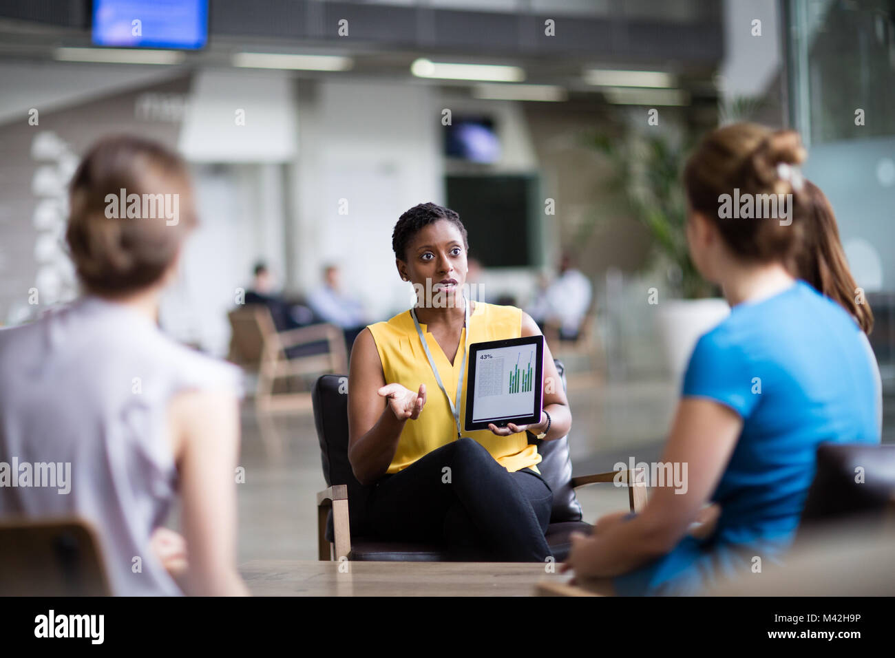 Imprenditrice in una riunione utilizzando una tavoletta digitale Foto Stock