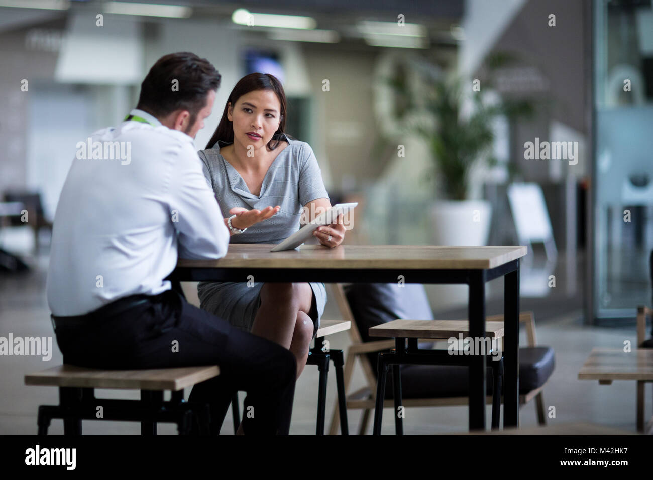 Imprenditrice in una riunione utilizzando una tavoletta digitale Foto Stock