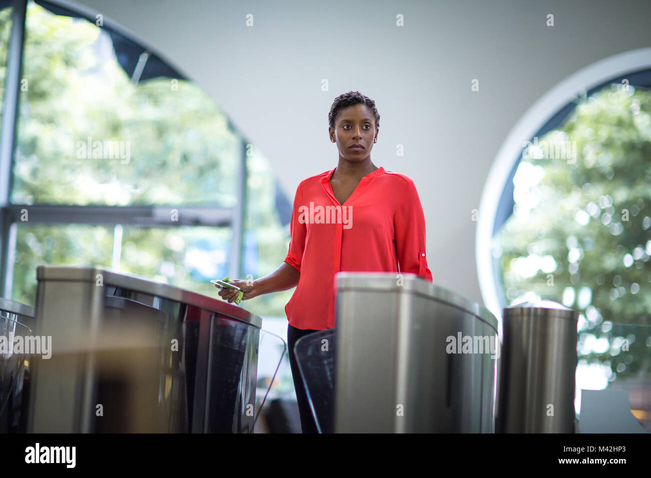 Donna che cammina attraverso i cancelli di sicurezza in un ufficio Foto Stock
