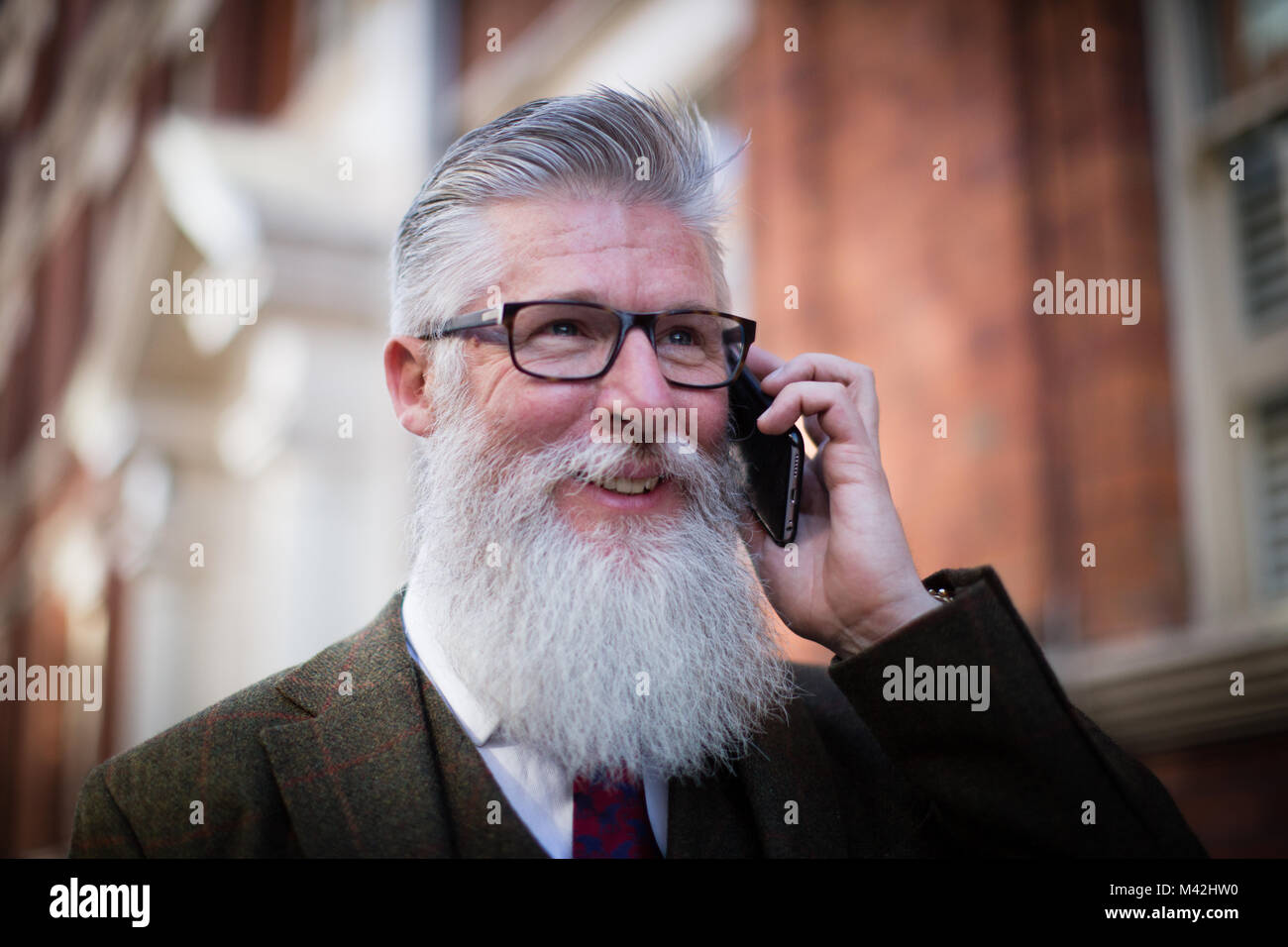 Maschio senior di camminare per strada utilizza lo smartphone Foto Stock