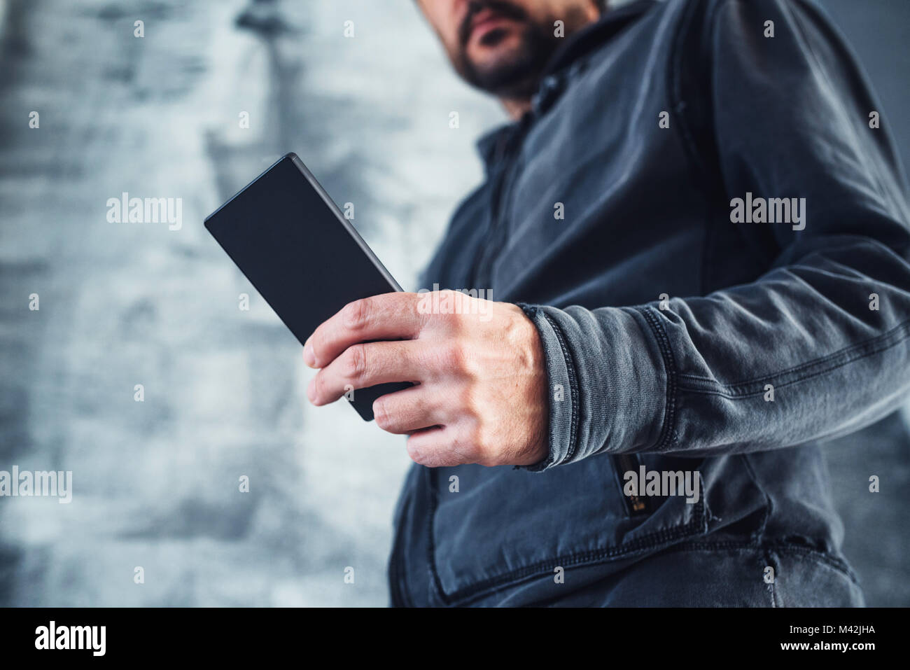 Basso angolo di visione del casual uomo adulto privato di lettura messaggio di testo SMS sul suo telefono cellulare personale Foto Stock