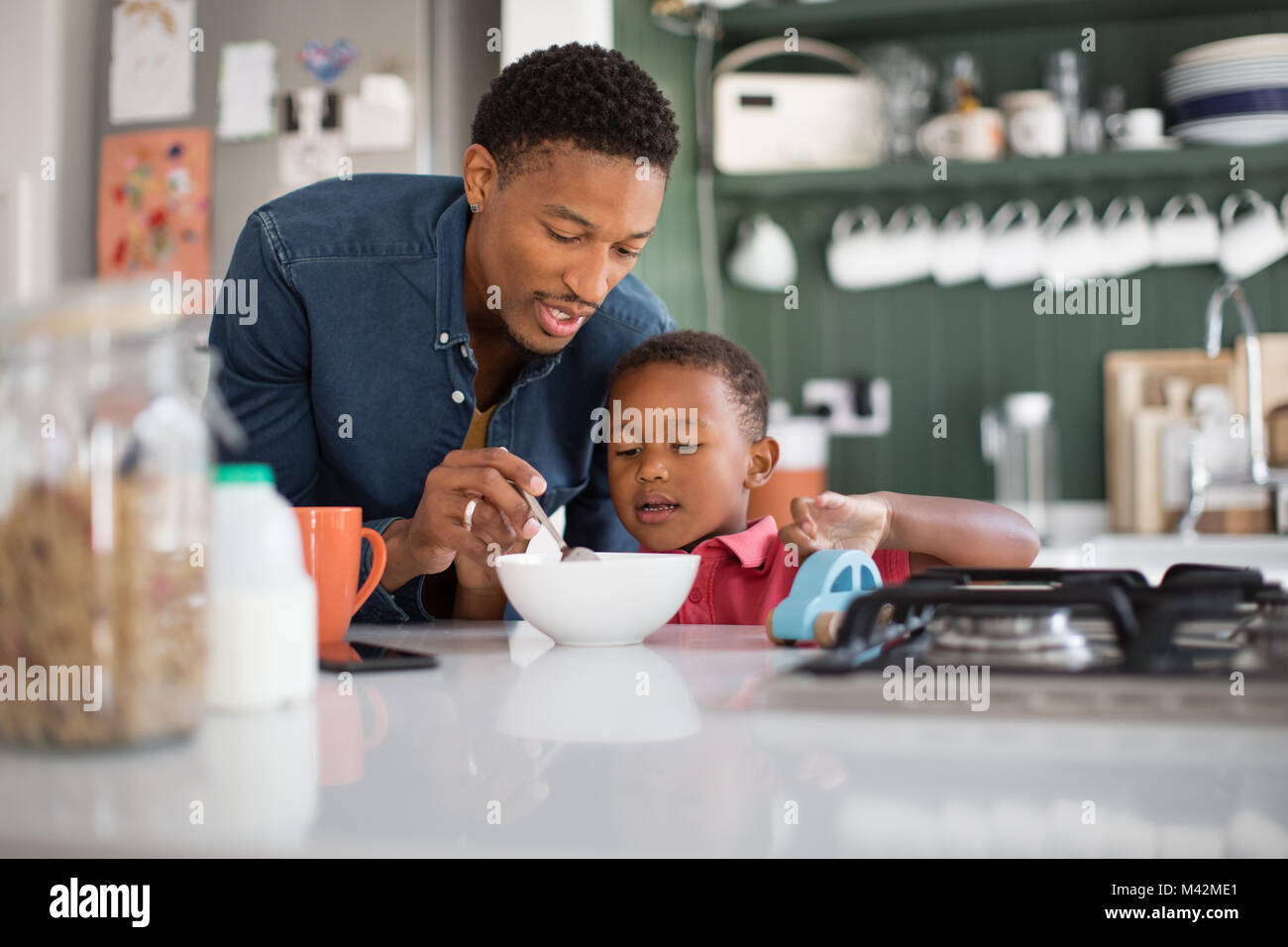 Papà aiutando figlio con prima colazione Foto Stock