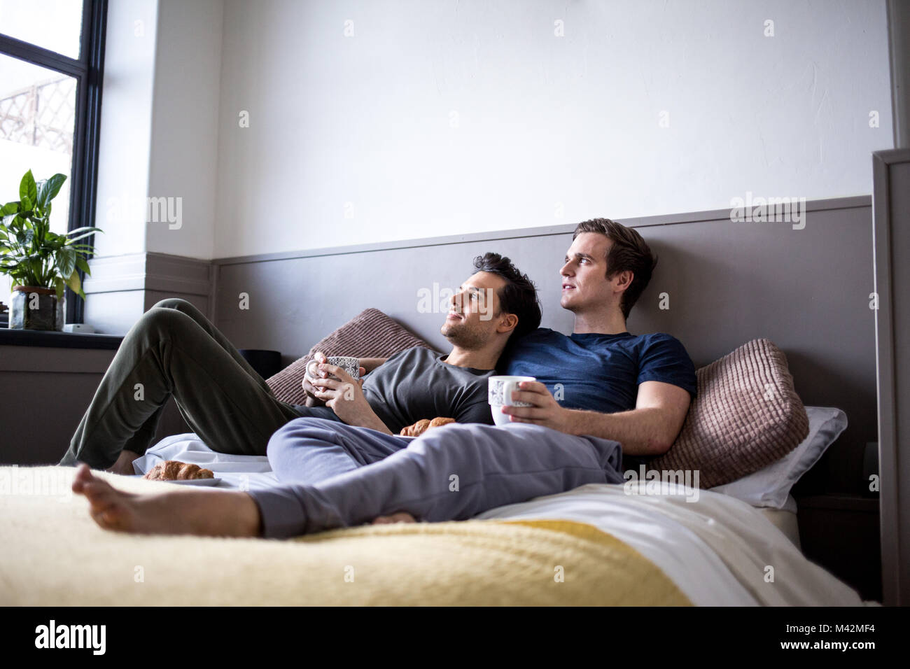 Giovane maschio giovane rilassante con il caffè a letto Foto Stock