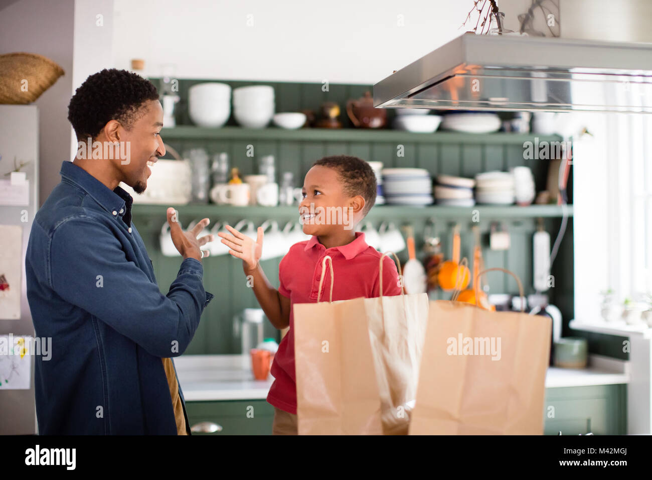 Padre e Figlio con sacchetti di generi alimentari a casa Foto Stock