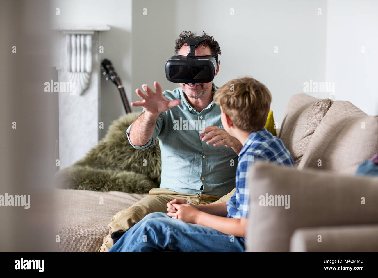 Padre utilizzando un auricolare VR gioco a casa Foto Stock