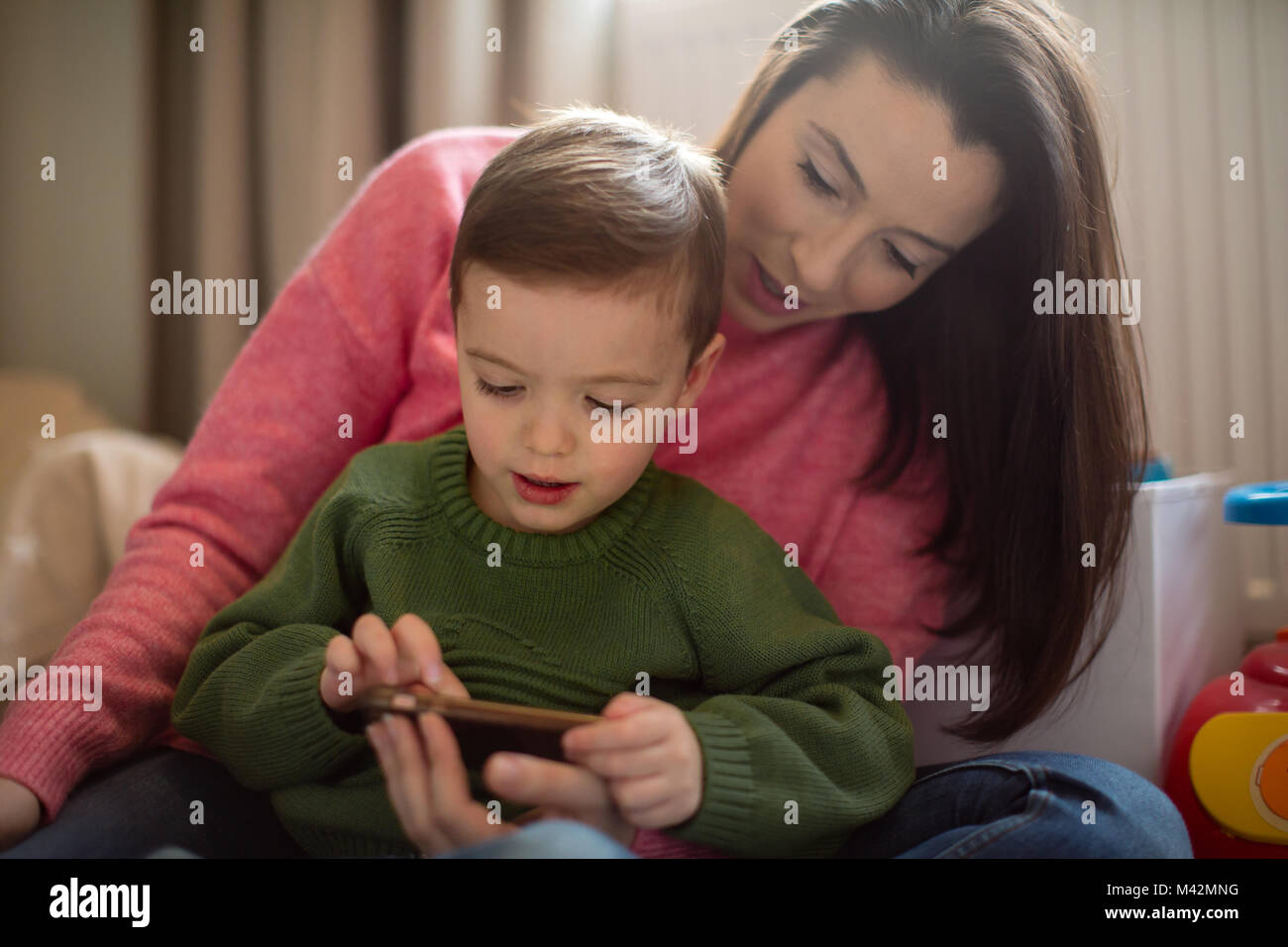 Ragazzo di età prescolare giocando con lo smartphone con la madre Foto Stock