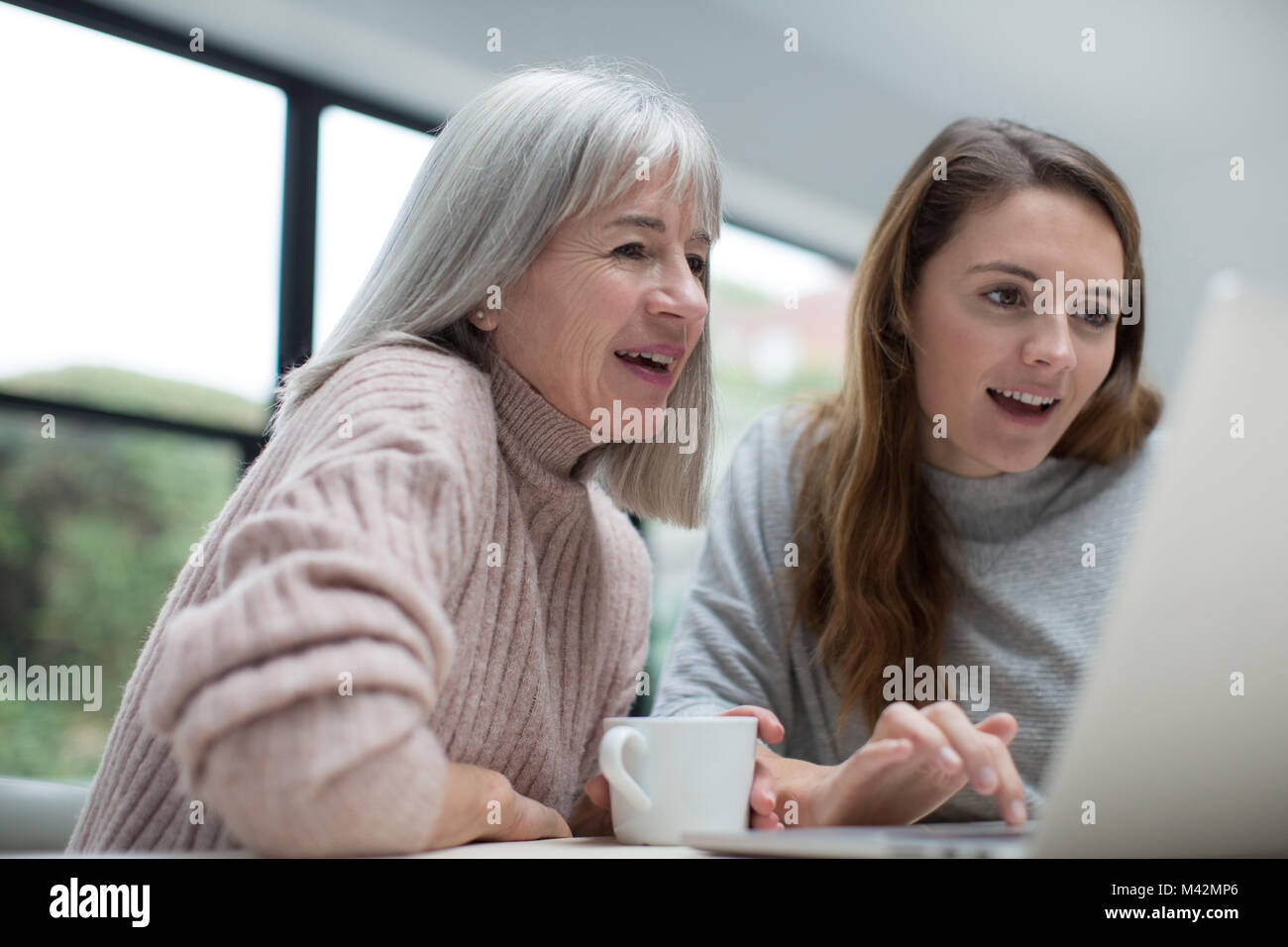 Madre e figlia usando un computer portatile insieme Foto Stock