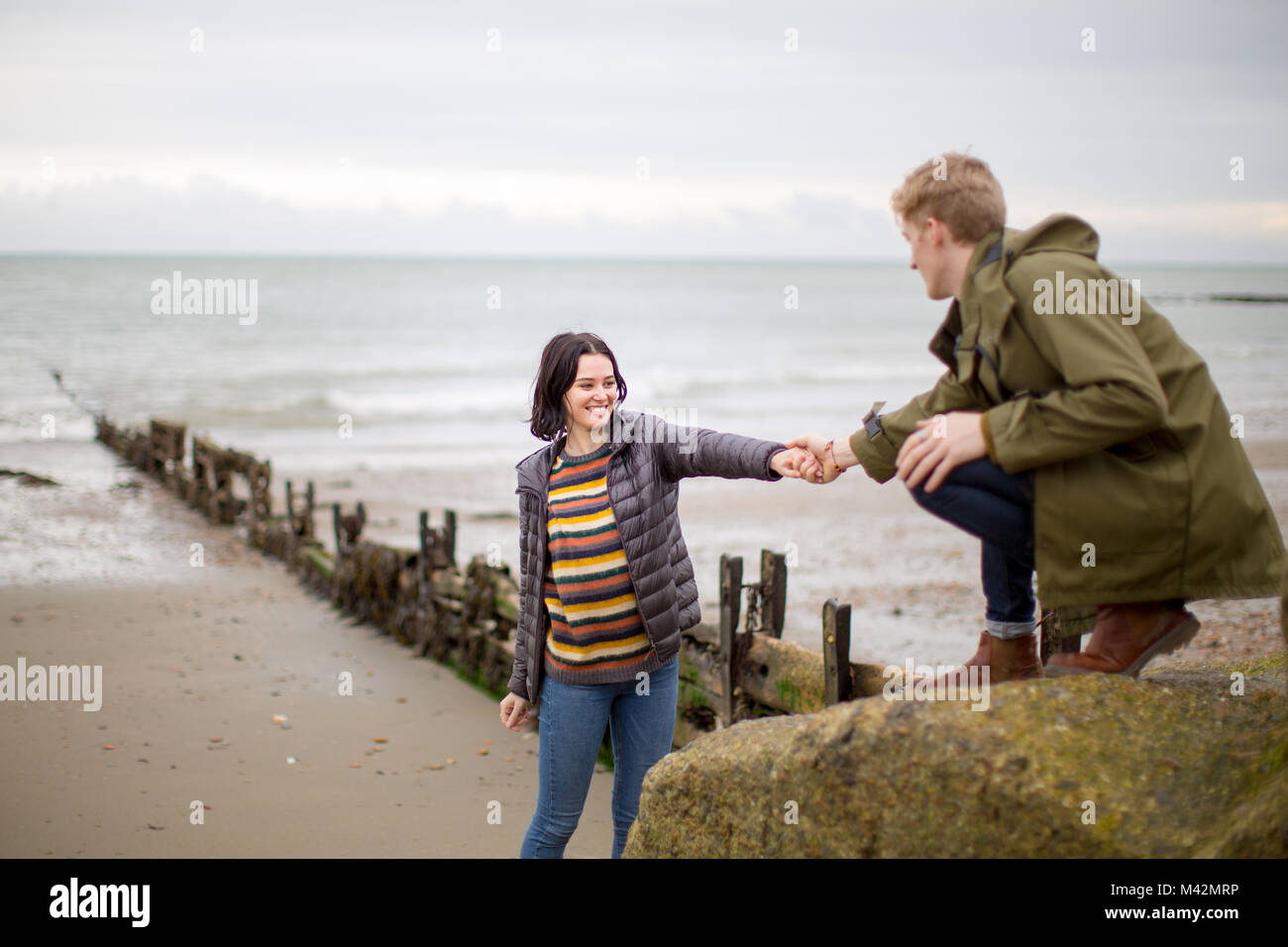 Fidanzato aiutando ragazza salita una roccia Foto Stock