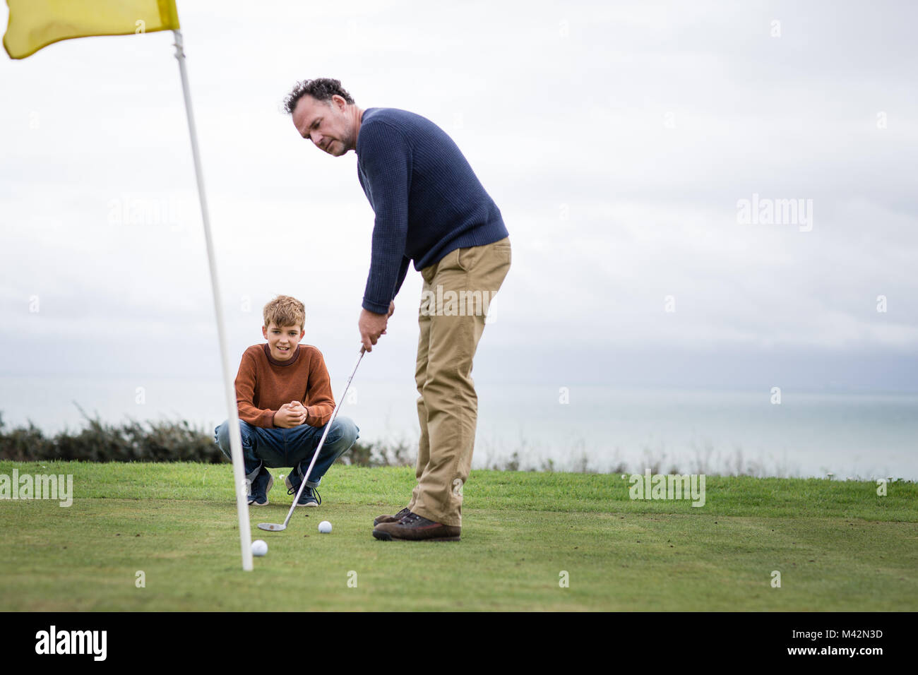 Figlio guardando padre giocare a golf Foto Stock