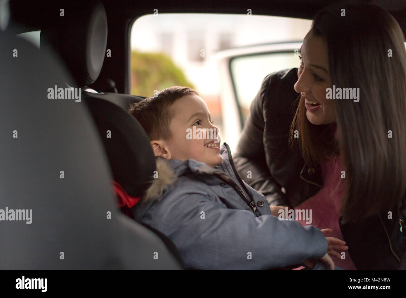 Madre di mettere il figlio in auto in tutta sicurezza sedile Foto Stock