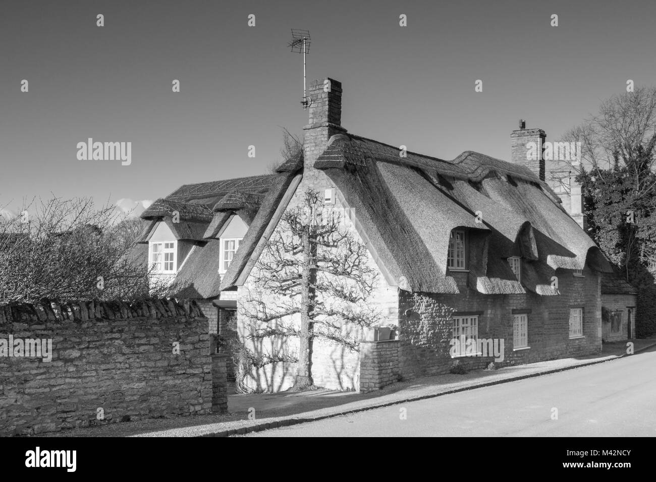 Un'immagine monocromatica di un cottage in pietra con il tetto di paglia. Foto Stock