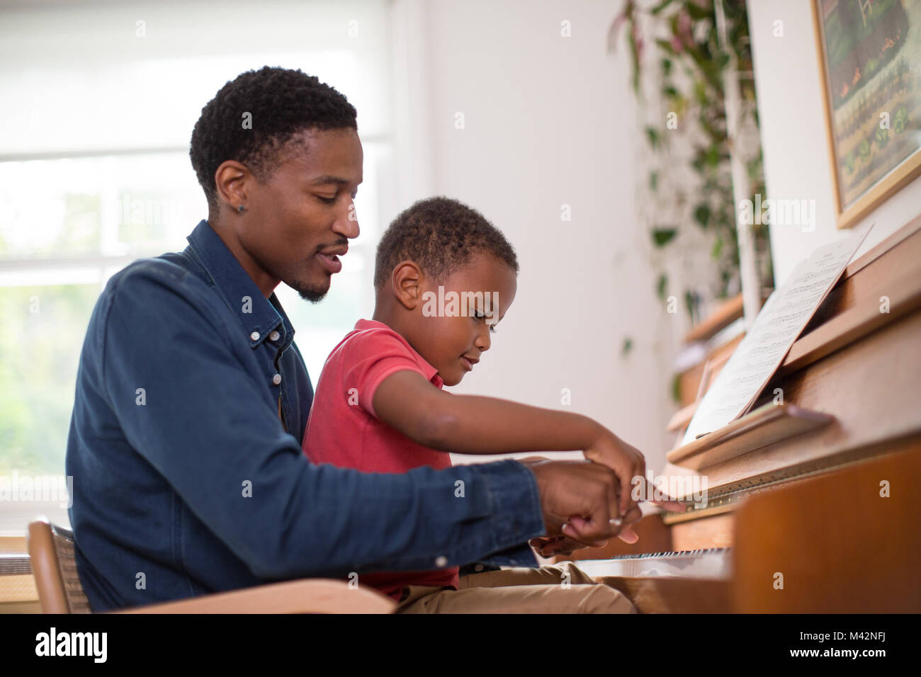 Padre figlio di insegnamento a suonare il piano Foto Stock