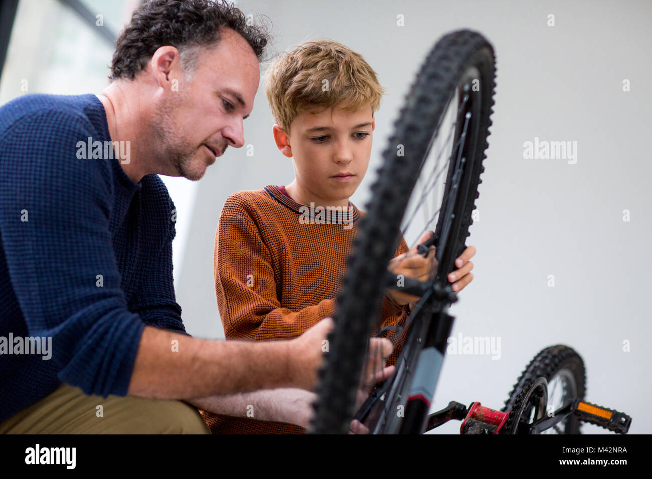 Fissaggio del ragazzo in bici con il suo papà Foto Stock