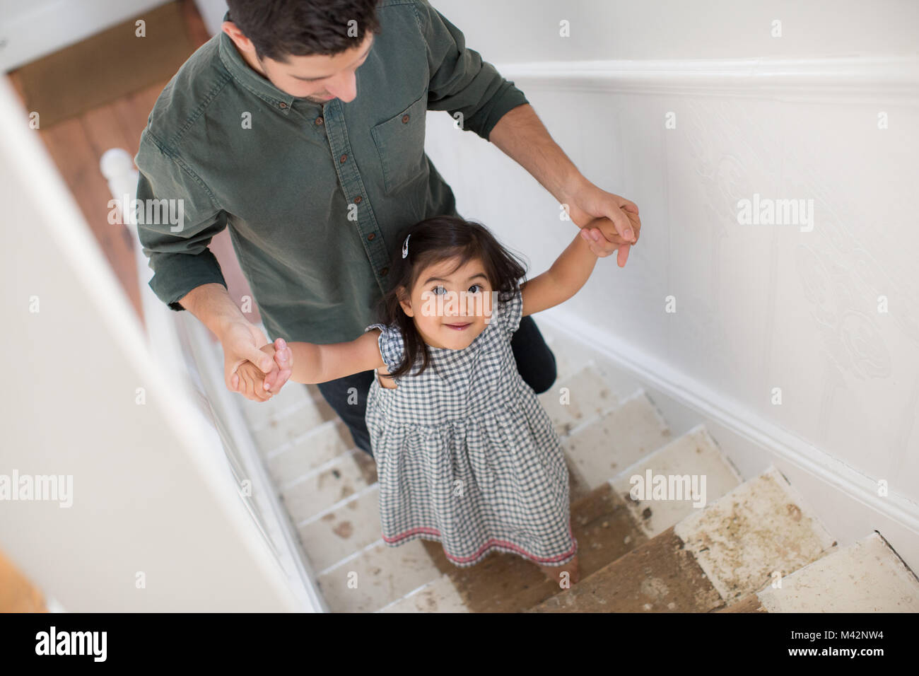 Padre aiutare mia figlia a piedi su per le scale Foto Stock