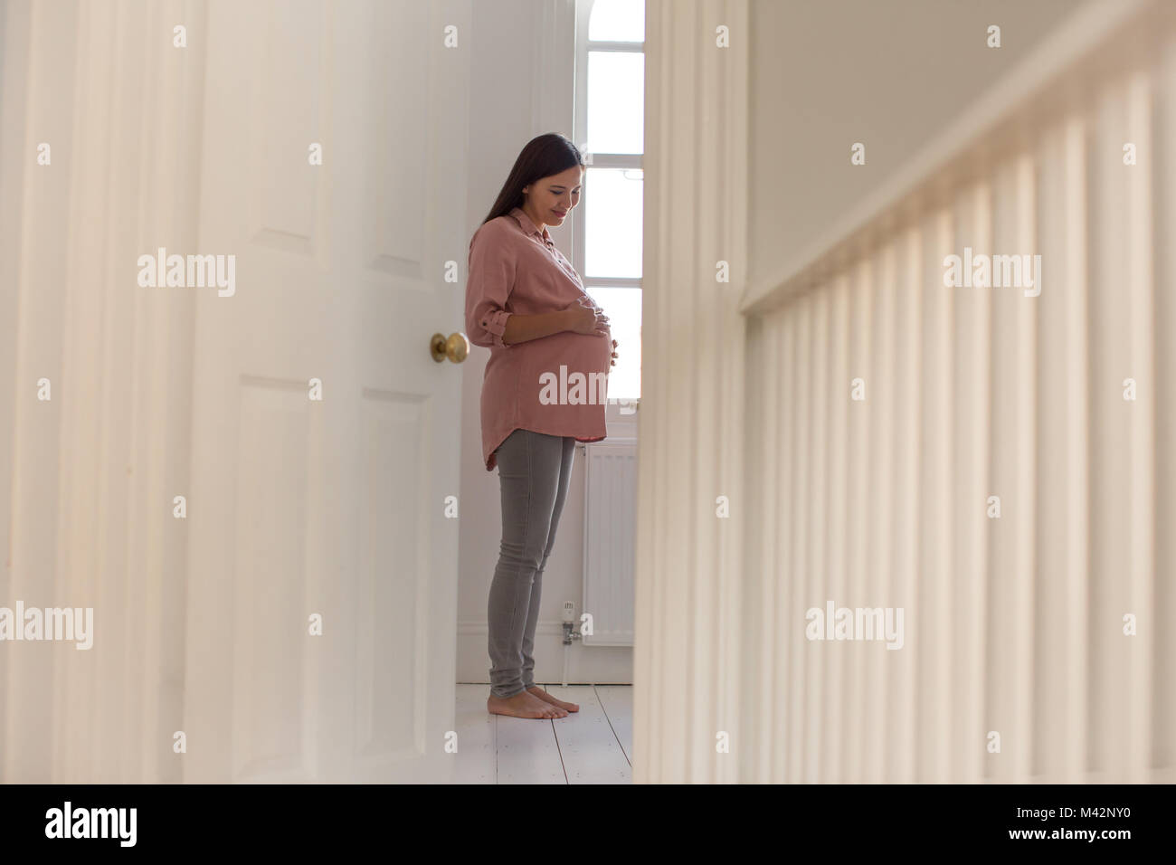 Donna incinta in piedi nella nursery room Foto Stock