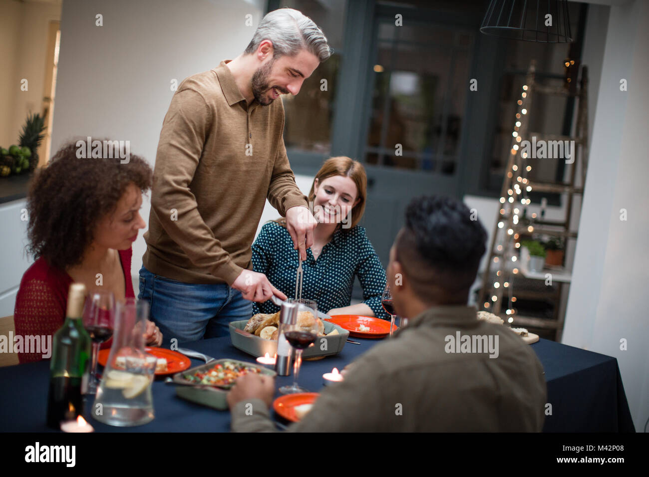 Maschio adulto che serve il pranzo di Natale per gli amici Foto Stock