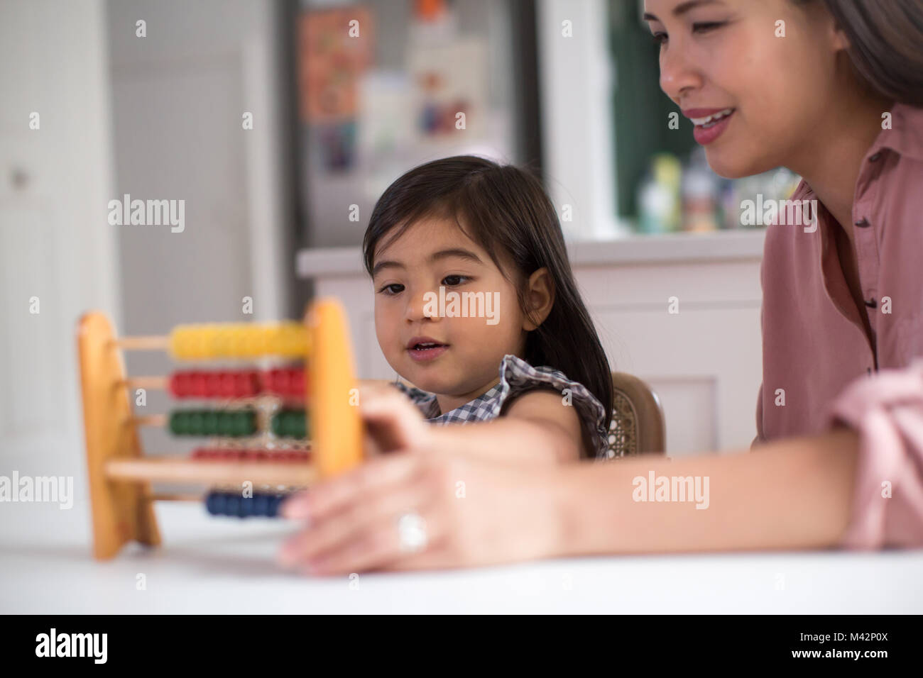 Ragazza utilizzando abacus a contare con la madre Foto Stock