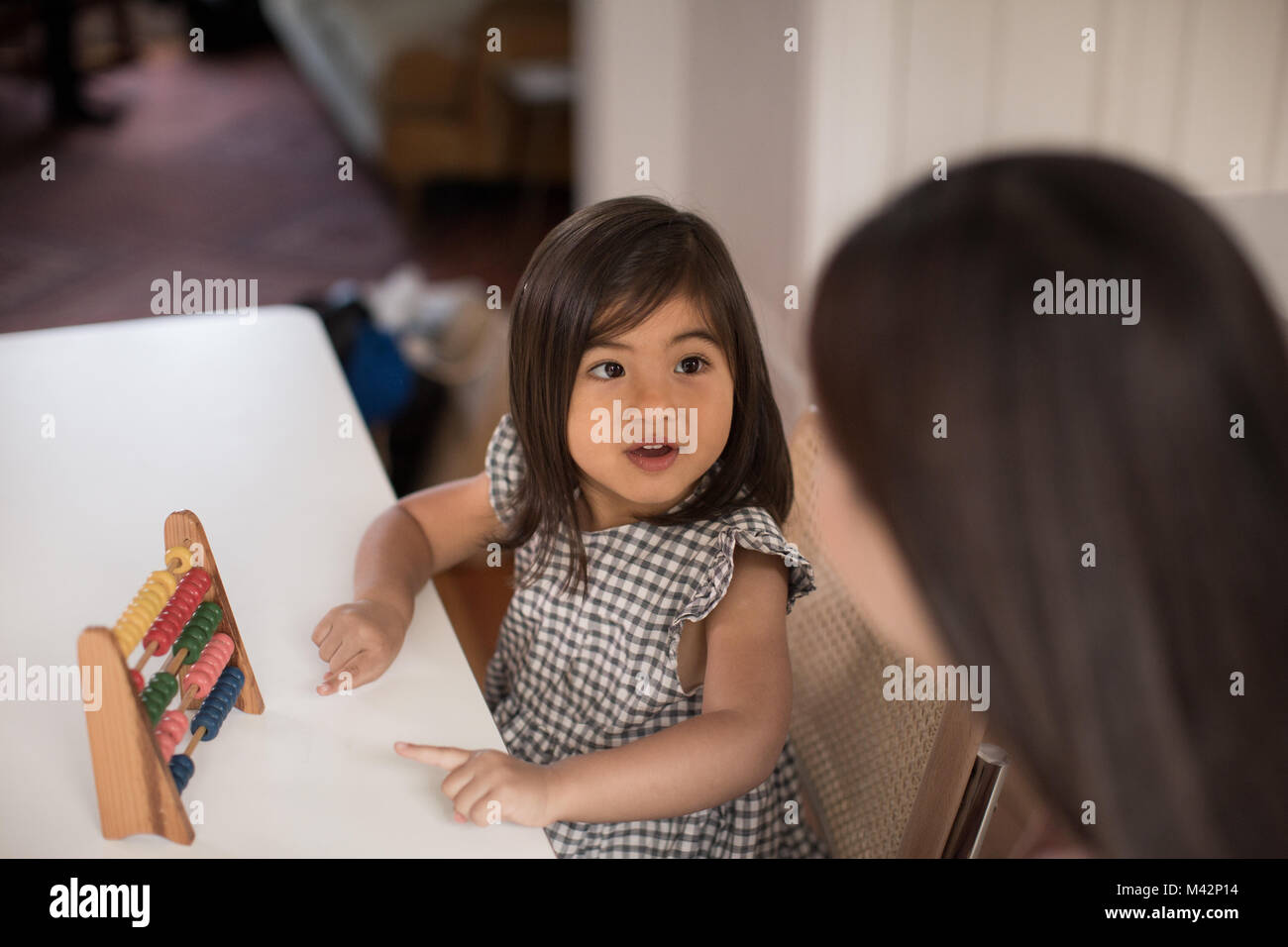 Ragazza utilizzando abacus a contare con la madre Foto Stock