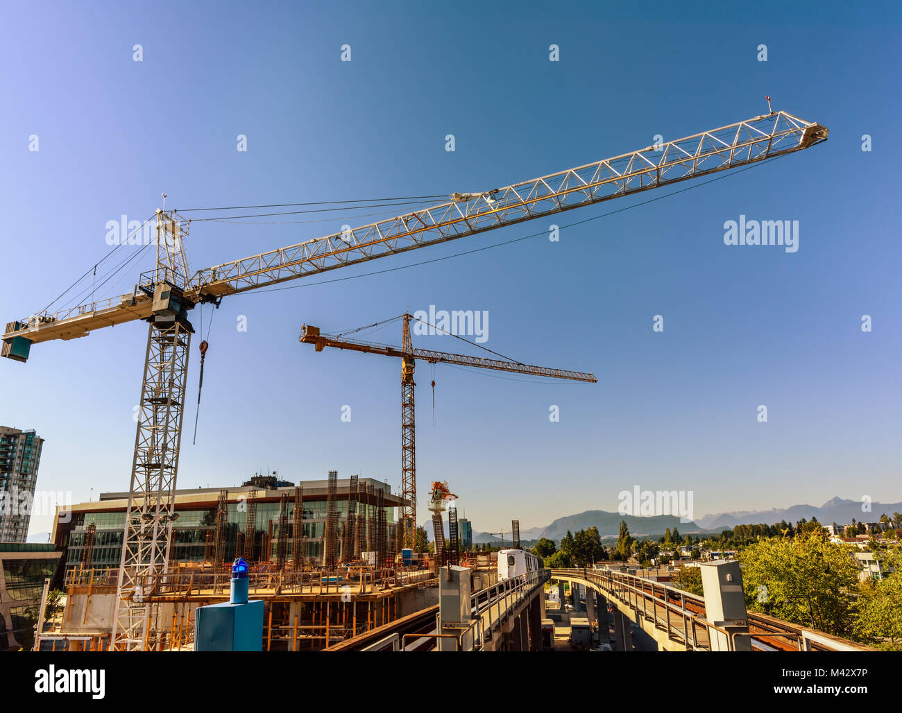 Gru a torre, gru edili, raccordi di ferro di edifici in costruzione, ponteggi, contro lo sfondo del cielo profondo, treno elettrico Foto Stock