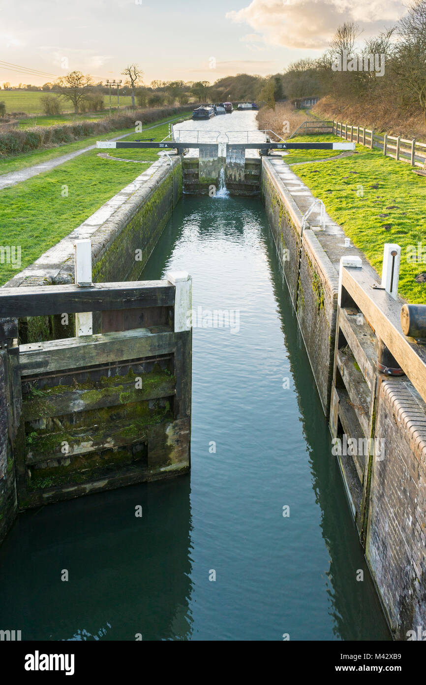 Acqua che sgorga attraverso un canale serratura con travi di equilibrio al Kennet and Avon canal nel Wiltshire durante la luce della sera, England, Regno Unito Foto Stock