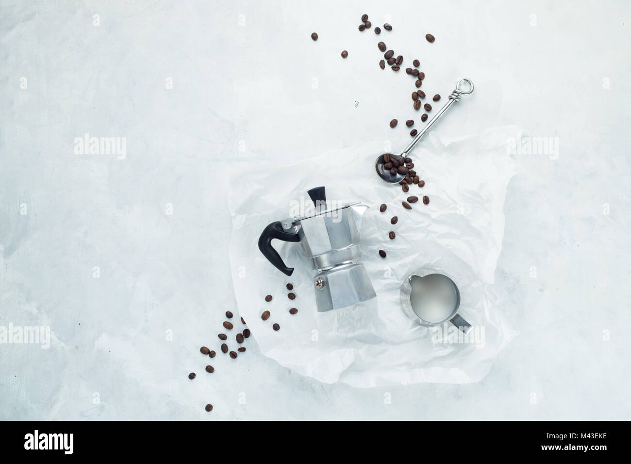 Il caffè concetto laici piatta su un cemento bianco sullo sfondo. Immagine minimalista con copia spazio. Moka pot, caffè tastin cucchiaio, bricco per latte e caffè Foto Stock