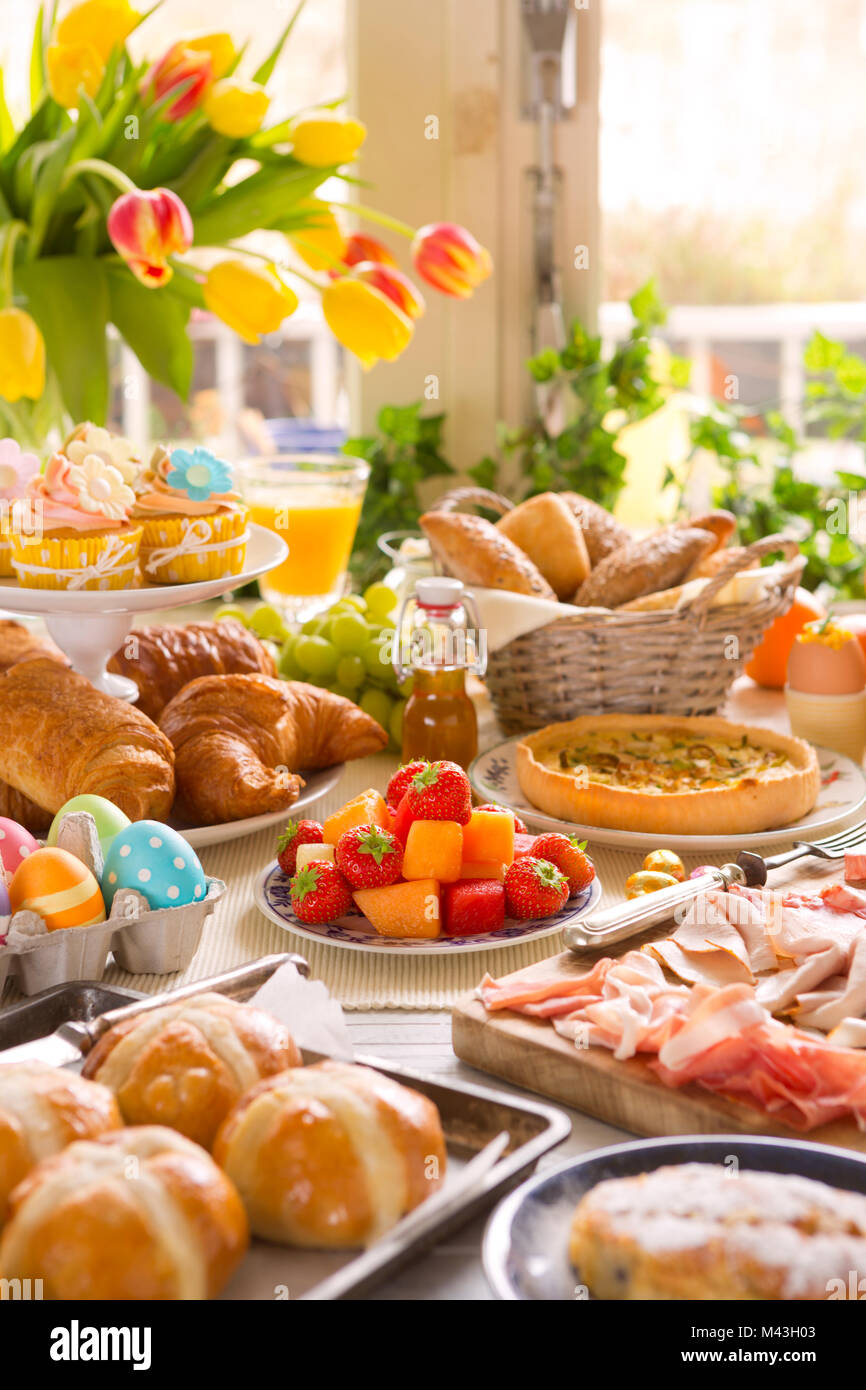 La colazione o il brunch tabella riempita con tutti i tipi di deliziosa gastronomia pronta per un pasto di Pasqua. Foto Stock