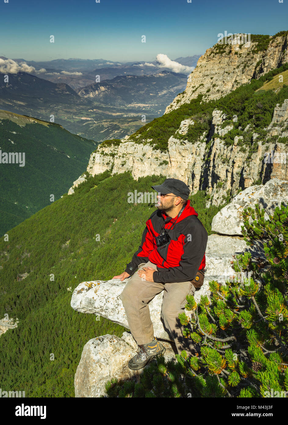 giovane uomo in attesa della buona luce per scattare una foto seduta su un picco di roccia con la macchina fotografica. Parco Nazionale della Majella. Abruzzo, Italia, Europa Foto Stock