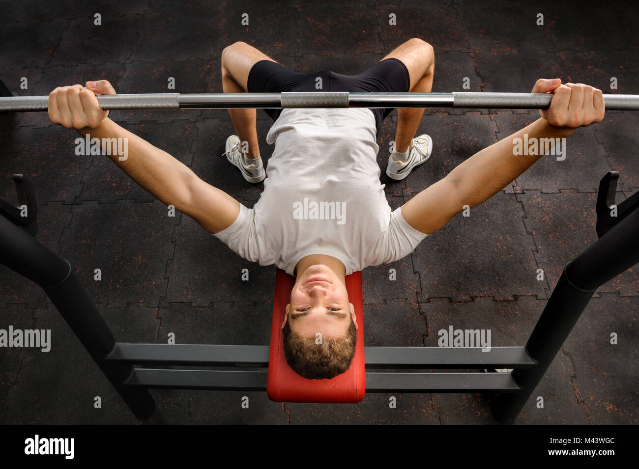 Giovane uomo facendo la pressa da banco allenamento in palestra Foto Stock