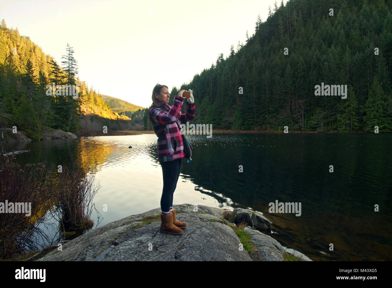 Femmina visite turistiche Brohm lago in inverno vicino a Whistler, BC Canada e scattare foto con lo smartphone Foto Stock