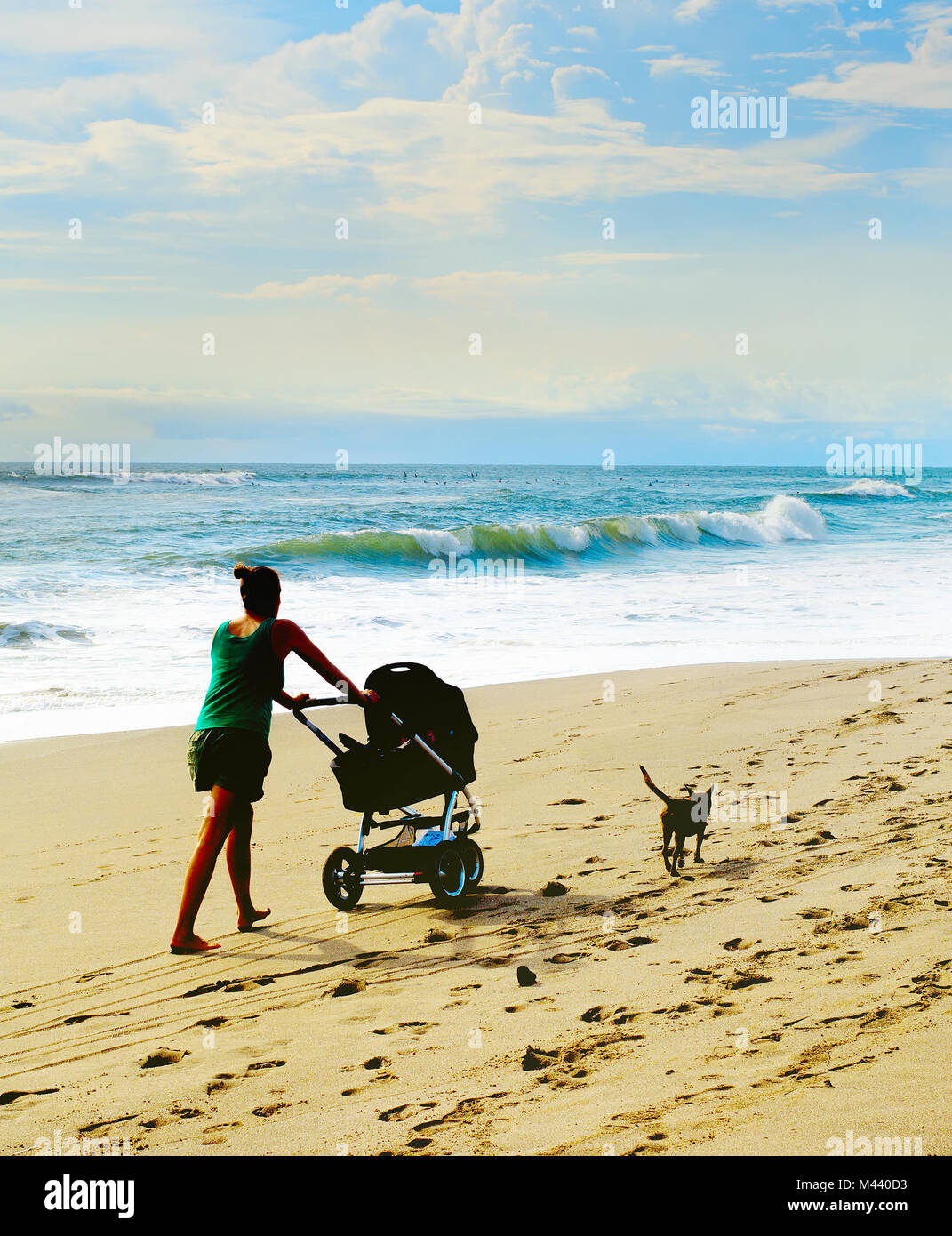 Donna con una carrozzina e un cane a piedi dalla spiaggia. Isola di Bali, Indonesia Foto Stock