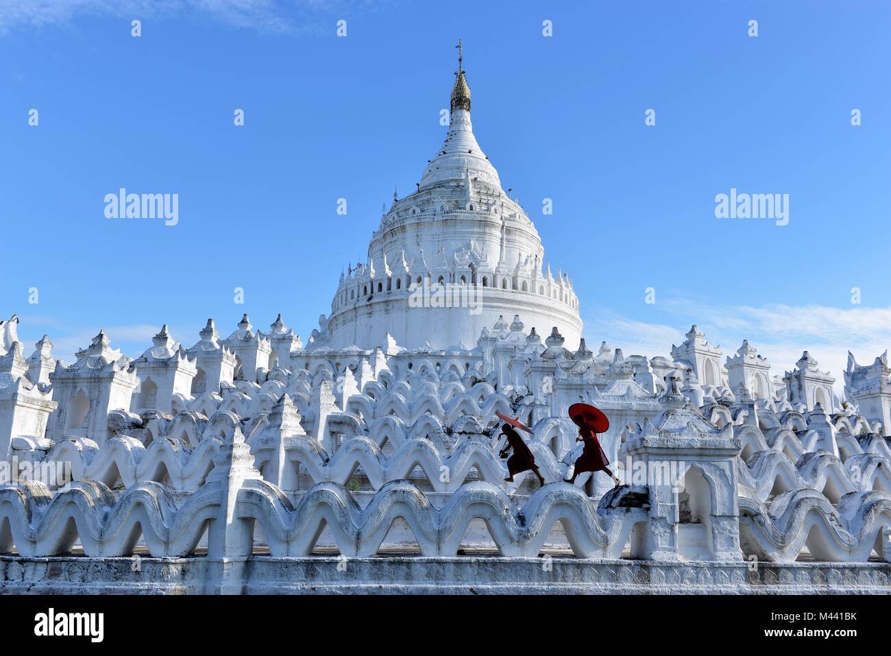 Ragazzi buddisti con vesti rosse e ombrelloni in esecuzione in un bianco Tempio del Buddha con lo skyline di blu Foto Stock Ragazzi buddisti con vesti rosse e ombrelloni in esecuzione in un bianco Tempio del Buddha con lo skyline di blu Foto Stock