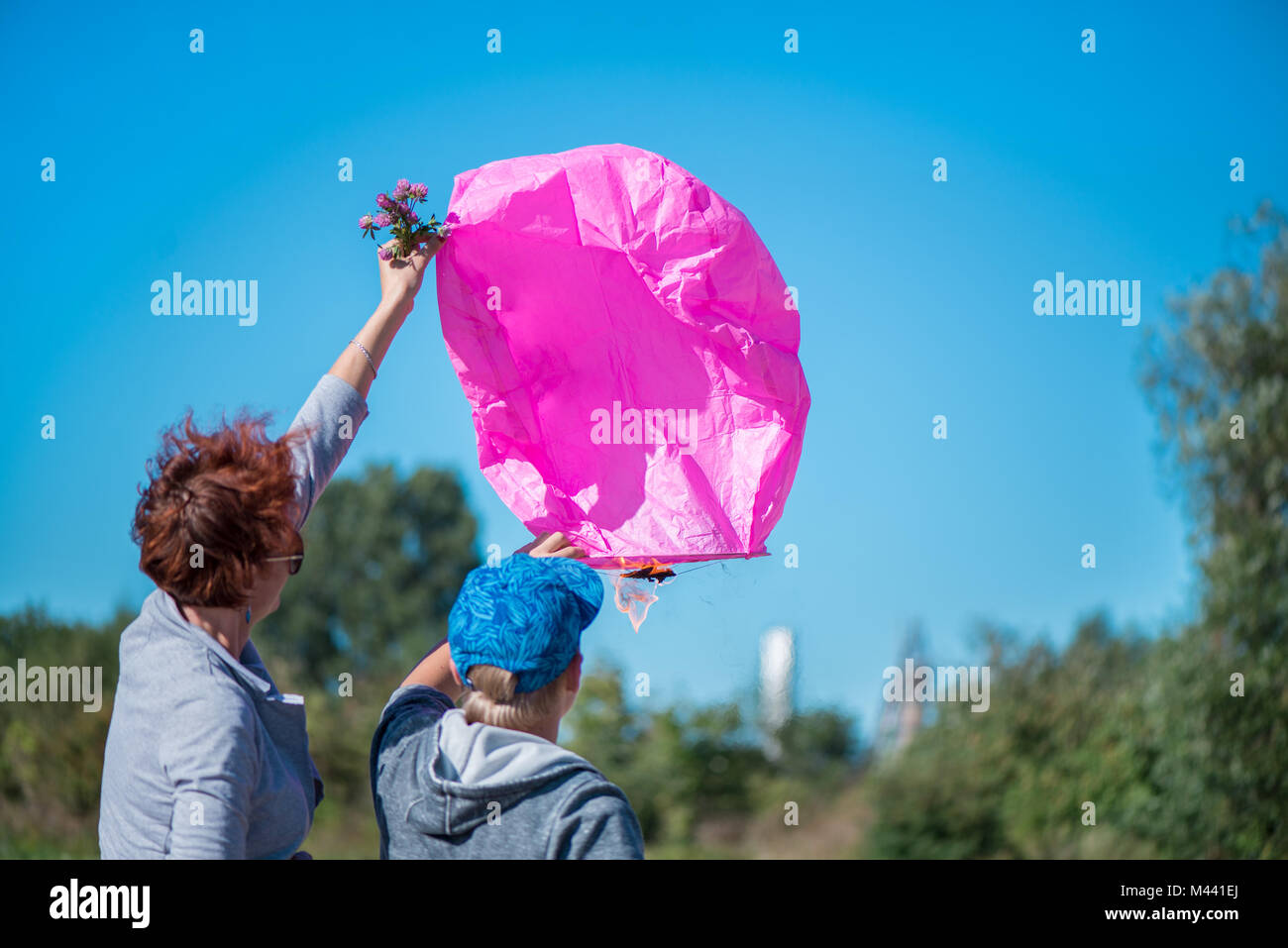 Madre e figlio festeggia il suo compleanno e la preparazione di una rosa lanterna di fuoco di lasciarlo andare con il vento sul cielo azzurro sfondo Foto Stock