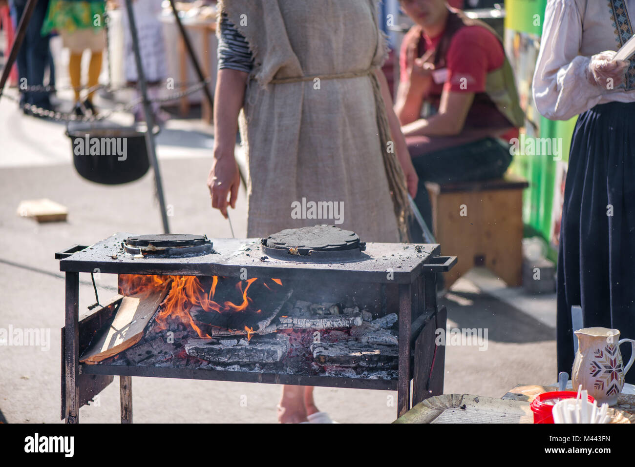 Donna in lino naturale di cottura del vestito waffle su caldo, la combustione di legna da ardere e carbone sul grill. Foto Stock