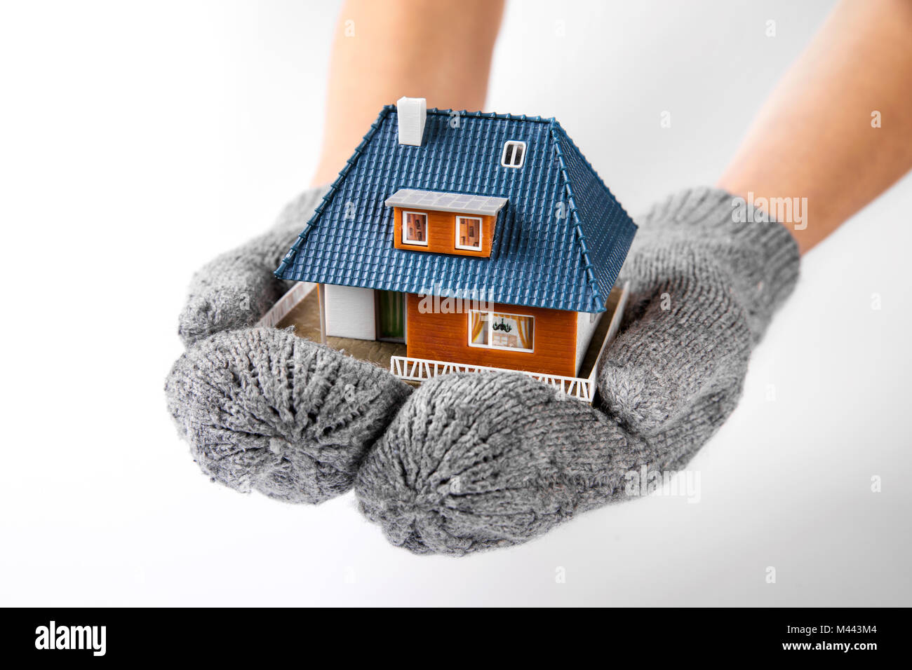 Assicurazione casa e il concetto di isolamento. mani con guanti tenendo in miniatura Modello di casa Foto Stock