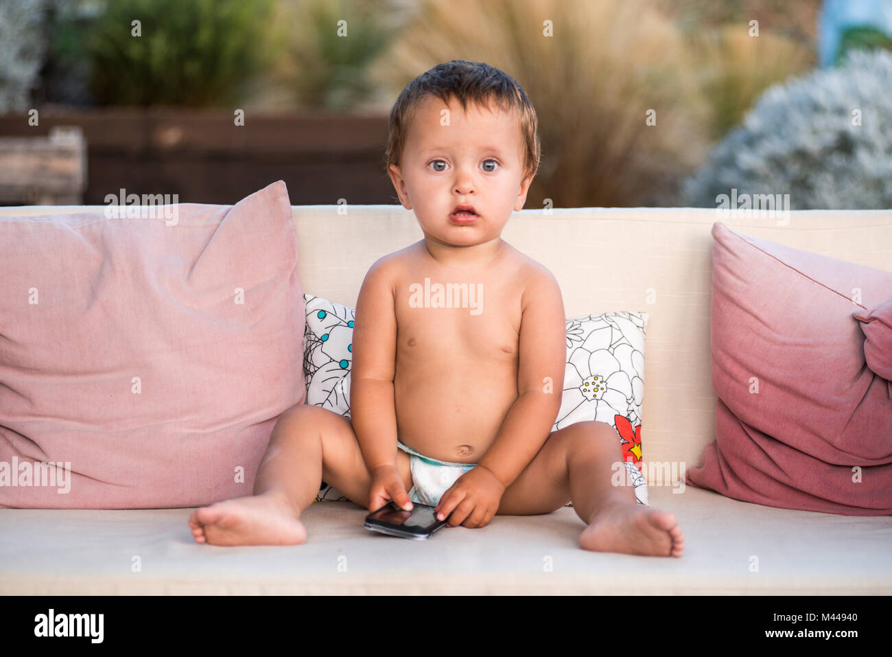 Baby boy holding smartphone guardando la fotocamera Foto Stock